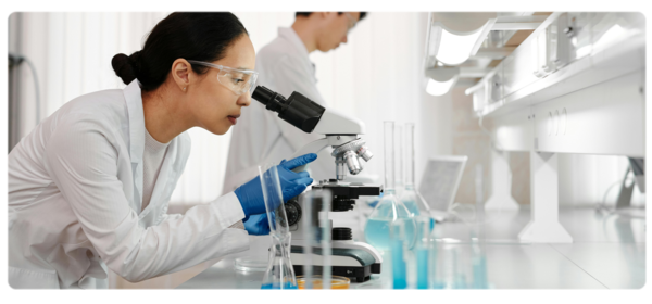 生物化学家在明亮的白色实验室环境中通过显微镜观察
