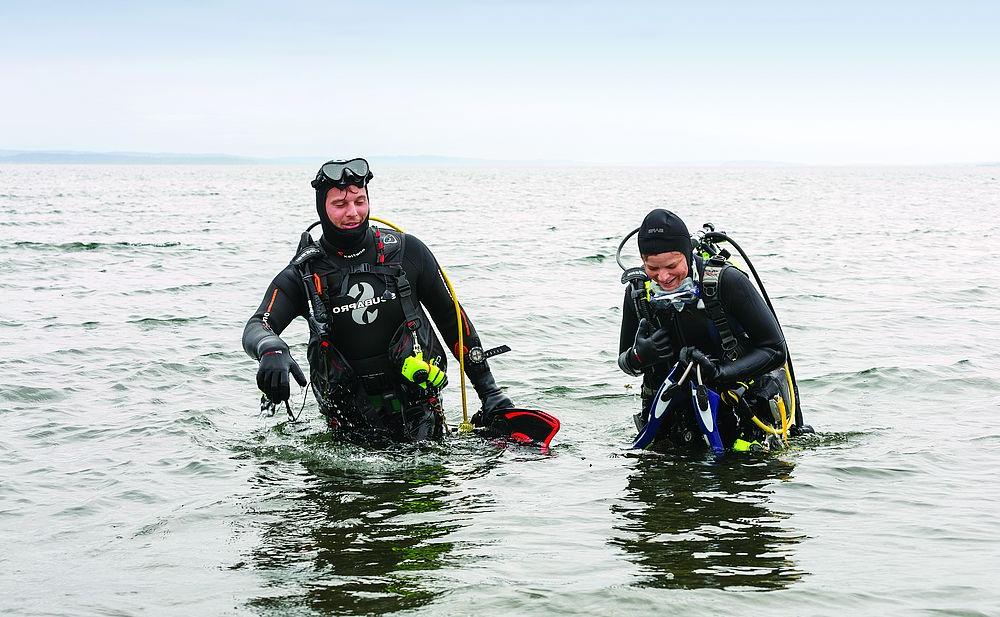 戴着水肺的潜水员带着研究设备走进海洋