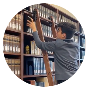 卡罗尔爬上图书馆的梯子，从最上面的书架上拿一本研究书籍